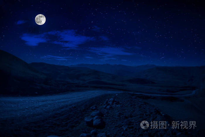 月圆之夜穿过森林的山路夜有大月的乡村公路夜景长快门照片