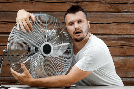 一个满头大汗的男人抱着一个凉爽的呼吸机,在炎热的夏天里让人耳目一