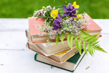 古老的书籍,一束野花在乡村的背景上.照片