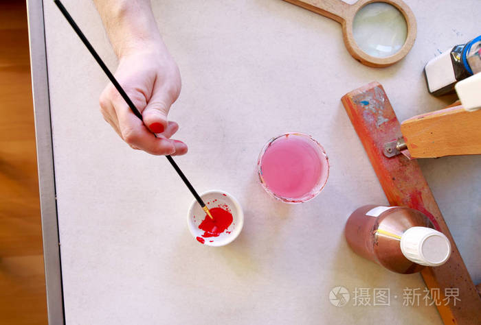 这位男画家在画画前在画室调色画家手里拿着画笔在调色板上画混合色