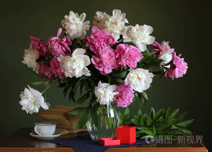 桌上摆着一束美丽的牡丹花和一个装有礼物的盒子。