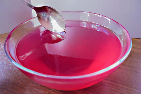 有浆果果冻红色果冻放在一个玻璃碗里,上面有一个小勺子照片