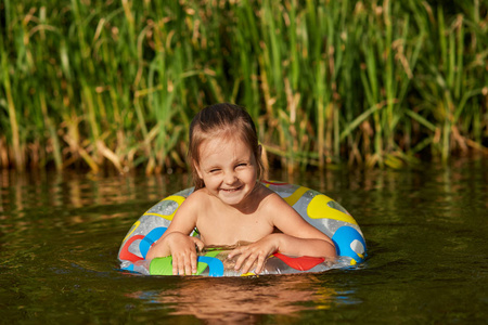 芦苇在河可爱顽皮的小孩在河里游泳,要学游泳,表情愉快,真诚微笑,背景