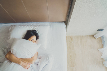 女人醒来后躺在床上伸展,后视图.女人坐着照片