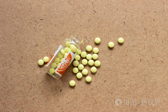 黄色药片.棕色表面上的黄色药丸.深色表面上的黄色药片