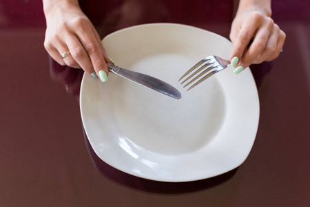 洁白的盘子和手拿刀叉.照片