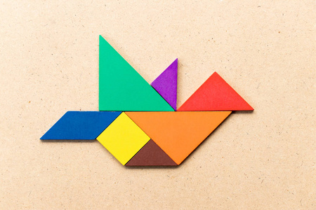 木制背景上飞鸟形状的七巧板照片