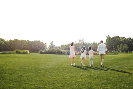 一家四口手牵手在公园户外共度周末的场景照片