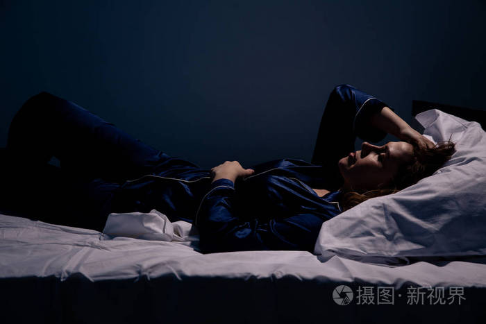 孤独悲伤的女人躺在床上失眠概念
