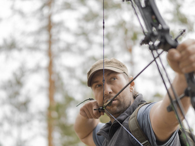 人在森林里用弓打猎.猎人瞄准了.照片