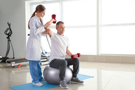 理疗师在康复中心与成熟患者一起工作照片