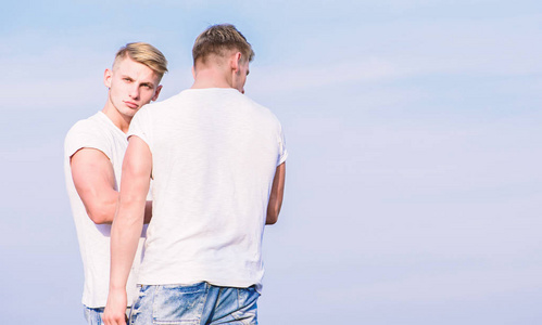 友谊和支持.男人肌肉发达的双胞胎兄弟穿着白衬衫天空背景.