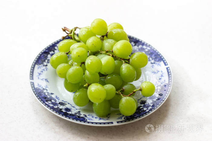 成熟的绿色葡萄盘在白色木桌上俯视桌上盘子里的绿葡萄桌上红盘子里的