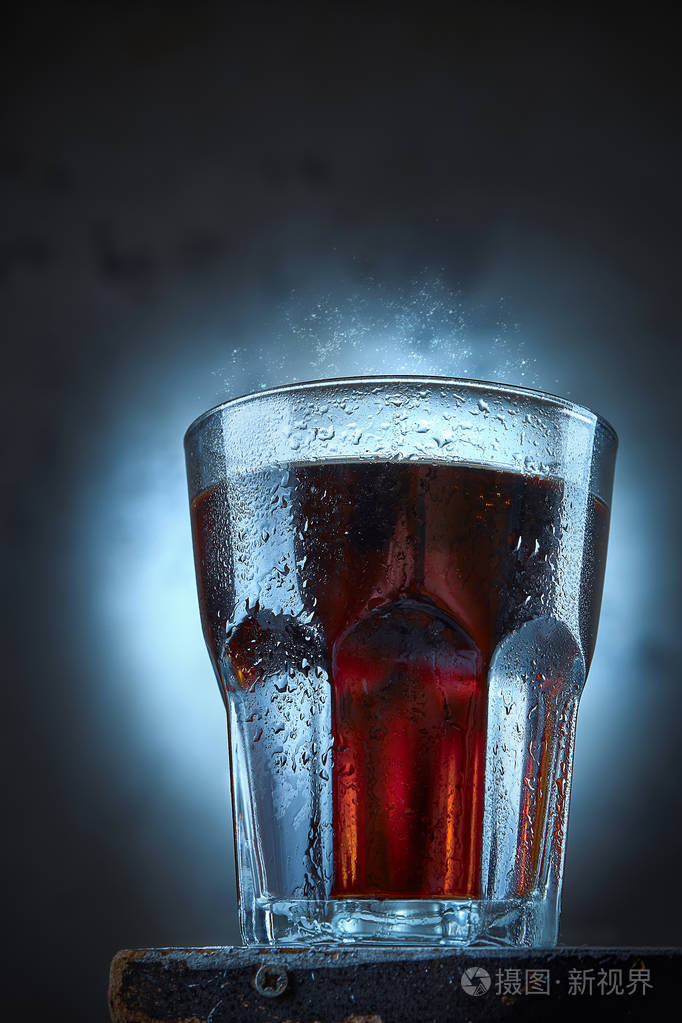 一杯冰镇的可乐,上面滴着水珠,发出嘶嘶声.夏季饮品概念.酒精混合物.