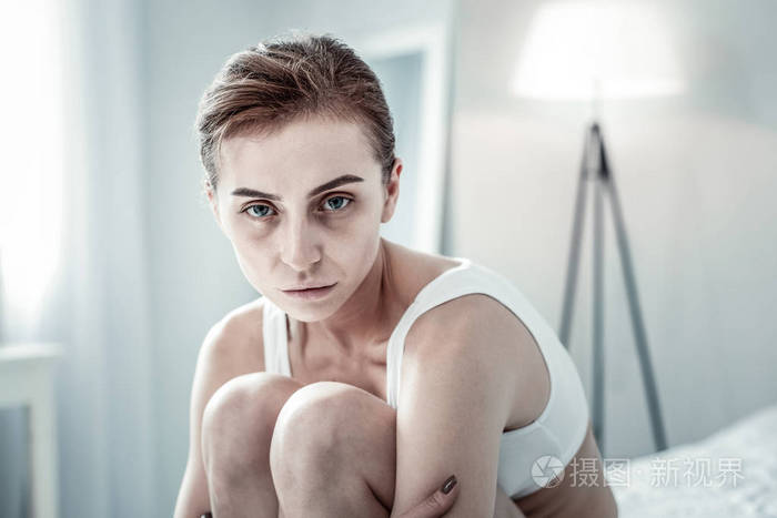 一个面容憔悴的女人坐在床上照片-正版商用图片2kzkn6-摄图新视界
