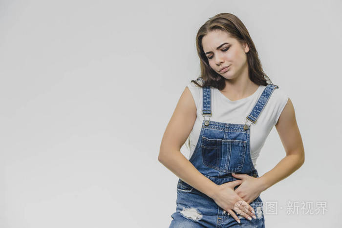 捂着肚子感受着痛苦的情绪她辛苦工作后感到疼痛一件漂亮的白色t恤