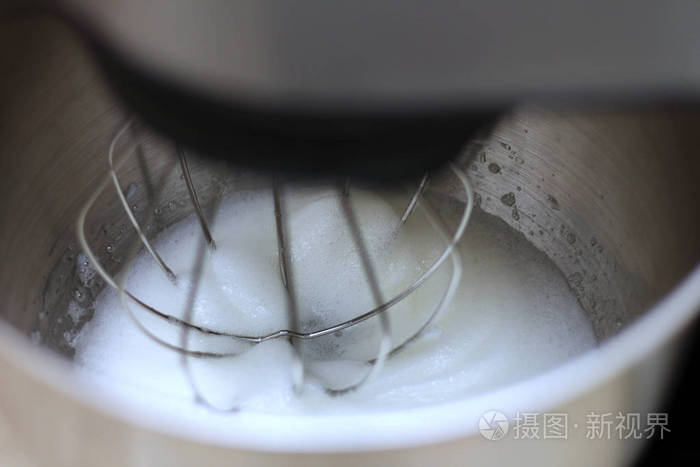 在餐馆里用专业的厨房搅拌器搅打蛋清在一个金属行星搅拌机碗里把搅碎