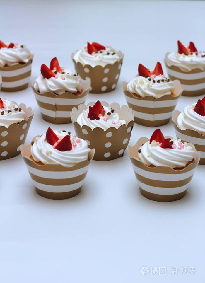特写纸杯蛋糕与生鸡蛋奶油装饰新鲜草莓和巧克力球在白色背景隔离