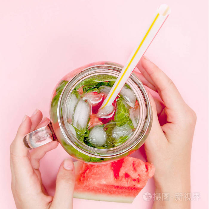 一个年轻的女人手拿着刚榨好的柑橘类水果的西瓜柠檬水.