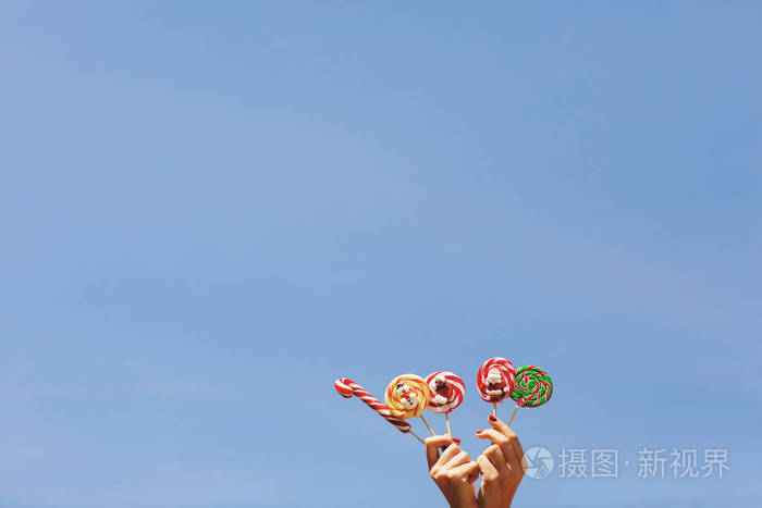 蓝色天空背景下妇女手拿彩色圣诞糖果文本空间圣诞节概念