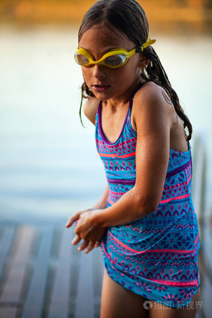 穿着泳衣戴着泳镜的游泳女孩在湖边锻炼