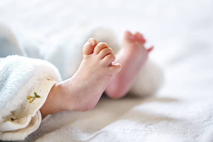 新生婴儿躺在白色和浅蓝色毯子上婴儿的小脚