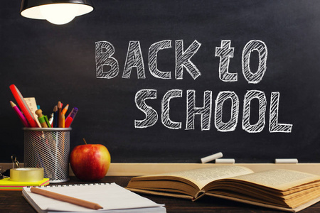 老师的桌子或工人,晚上灯下放着写作材料,一本书和一个苹果.