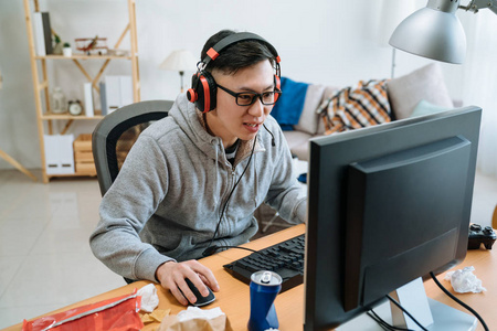 在凌乱的卧室里玩电脑游戏的男人照片