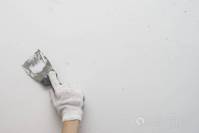工作工具手持抹刀背景为白色墙壁工作抹灰工用自己的手给墙抹腻子