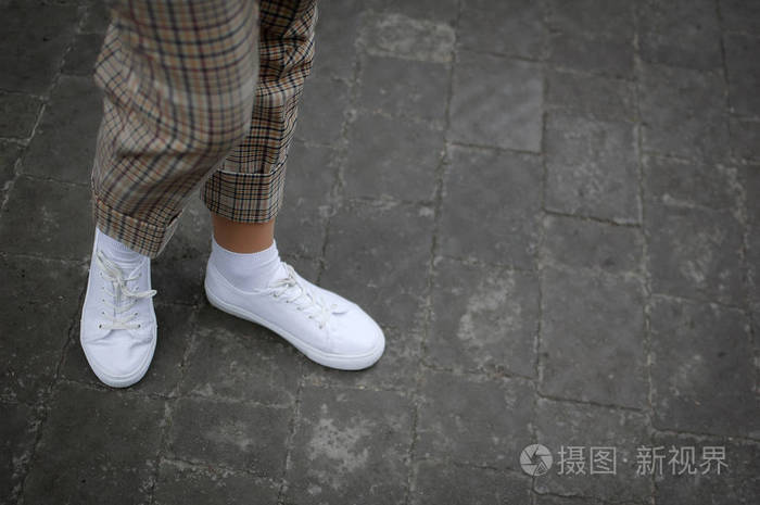 侧视图年轻女子脚白色运动鞋在沥青背景