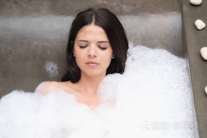 一个现代女孩真正的放松漂亮的黑发女人用泡沫洗澡