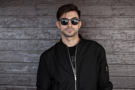 性感帅气的年轻时髦男子,戴着黑色时尚墨镜,发型时髦,穿着复古夹克,站