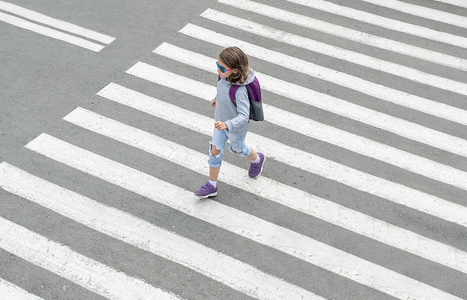 女学生在上学的路上过马路.斑马线在城市里步行.行人经过人行横道.