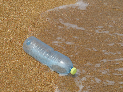 塑料瓶在沙滩上以海浪为背景,用塑料垃圾污染海洋的概念照片