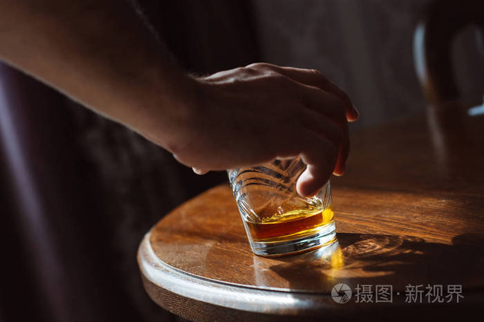 一个男人手拿着一杯威士忌的特写镜头.品尝和除味概念.