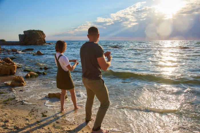 一对幸福的情侣在海边的沙滩上迎接日出玩耍镜框里阳光耀眼