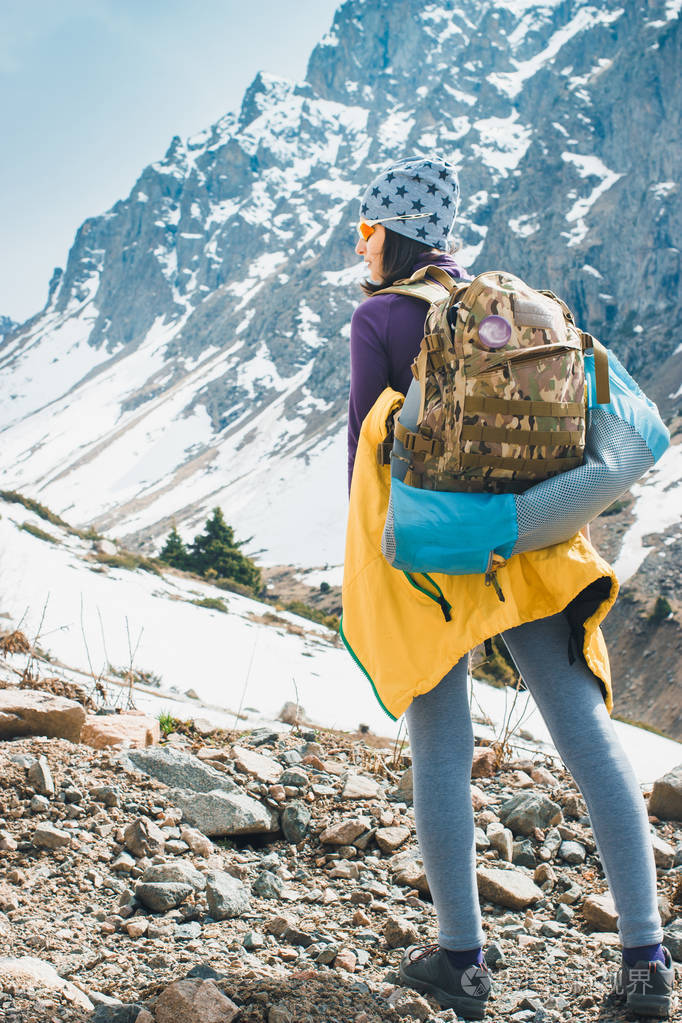在亚洲徒步旅行.年轻漂亮的女旅行者背着背包在登山前看了看山顶