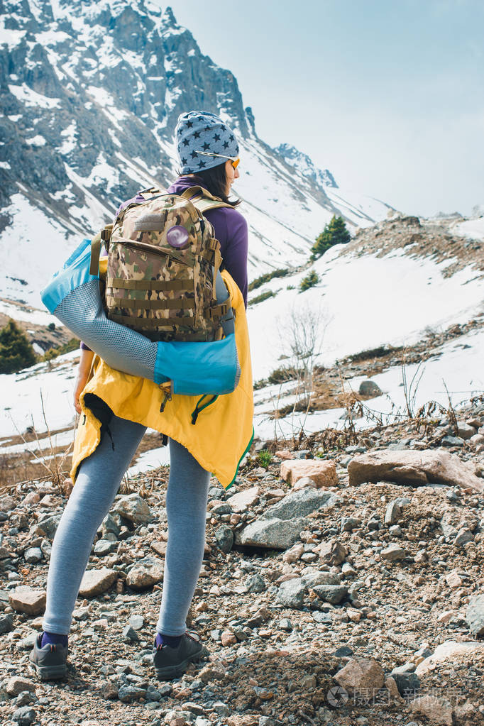 在亚洲徒步旅行.年轻漂亮的女旅行者背着背包在登山前看了看山顶
