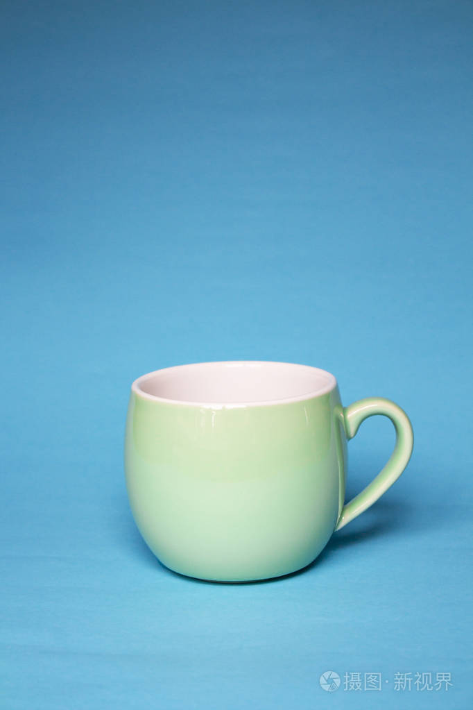 蓝色背景的杯绿色咖啡馆餐具或茶杯