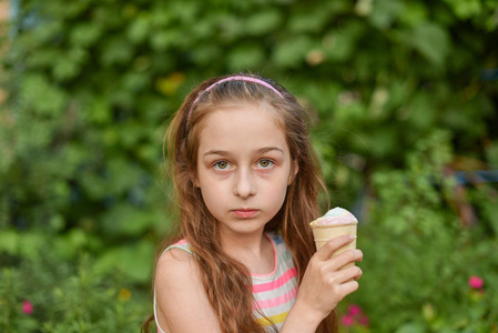一个小女孩穿着鲜艳的条纹连衣裙在户外吃冰淇淋.