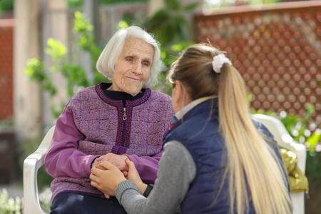 年轻漂亮的女人在户外拥抱老奶奶.女性世代之爱照片