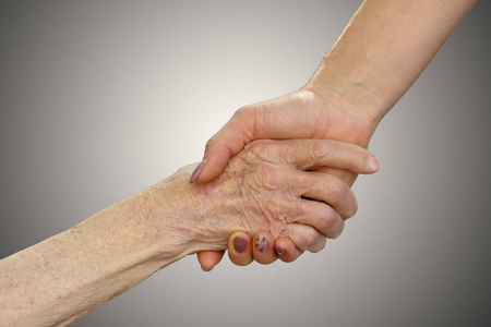 老少牵手年轻的成年人和老年妇女的手.老少牵手在外面.