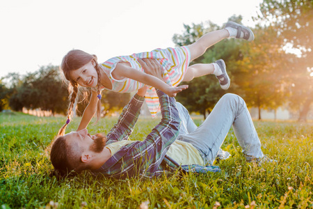夕阳下,小女孩女儿牵着父亲的手在大自然的背景下.照片
