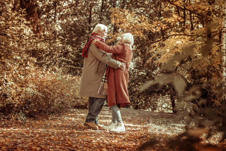 快乐的老人在公园里拥抱他的妻子.照片