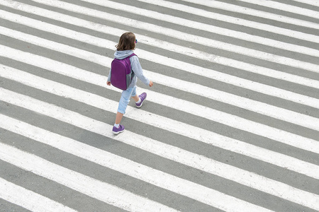 女学生在上学的路上过马路.斑马线在城市里步行.