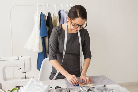 服装师,时装设计师和裁缝概念-漂亮的年轻造型师在工作场所靠近衣架