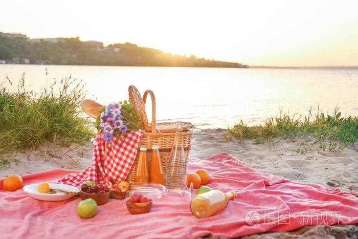 柳条篮子和美味的食物和饮料为浪漫的野餐河边照片-正版商用图片2lh9i