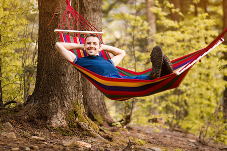 冥想睡觉一个安静的年轻人躺在公园森林中央的吊床上.