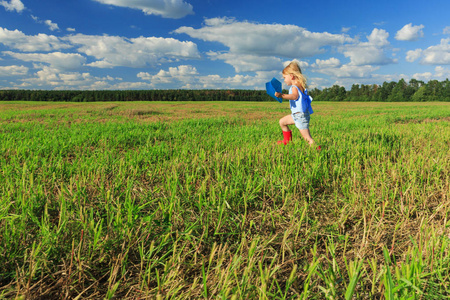 一个小女孩手里拿着一架纸飞机,开着一辆五轮车跑照片