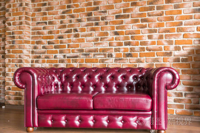 红皮沙发立在砖墙背景上